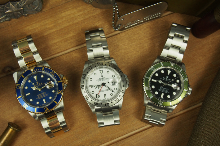 3 ROlex watches on wooden background with bullet