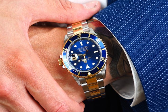 Two-Tone Blue preowned Rolex Submariner on wrist with suit
