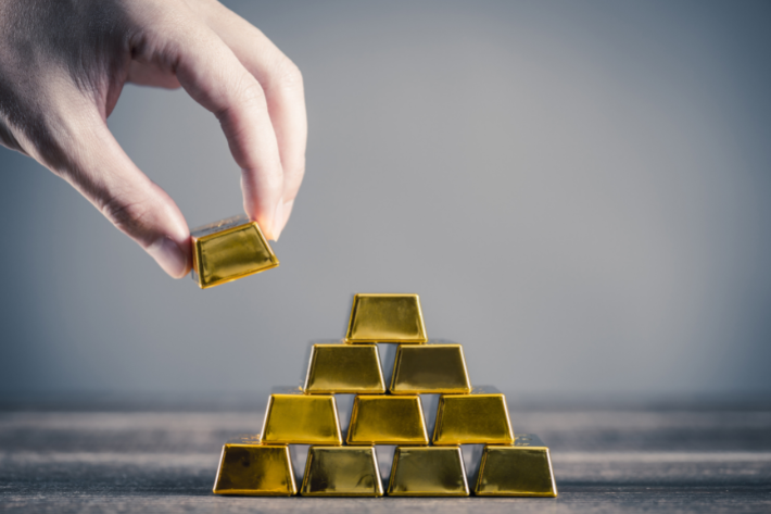 man stacking gold bullion bars in pyramid