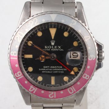 Pre-Owned 1968 Highly Collectable and Rare Vintage Rolex GMT Master Watch Stainless Steel MK1 (Long E) Black Dial With Creamy Patina And Red & Blue (Pepsi) Bezel With Oyster Band Model 1675 face up close